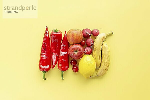 Healthy and organic food flay lay concept on yellow background. A square made of different vegetables and fruits like lemon  apples  bananas  red sweet pepper  radish