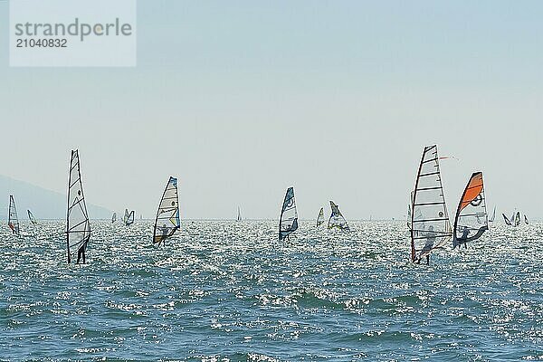 People windsurfing on a sunny day with clear blue skies and mountain backdrop  Lake garda  Torbole  Lake garda  Lago di Garda  Trentino  Italy  Europe