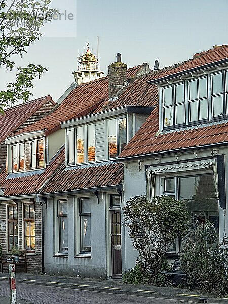 Street with traditional houses and a lighthouse in the background  egmond aan zee  the netherlands