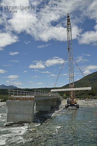 Builders construct a concrete bridge over a small river in Westland  New Zealand  Oceania