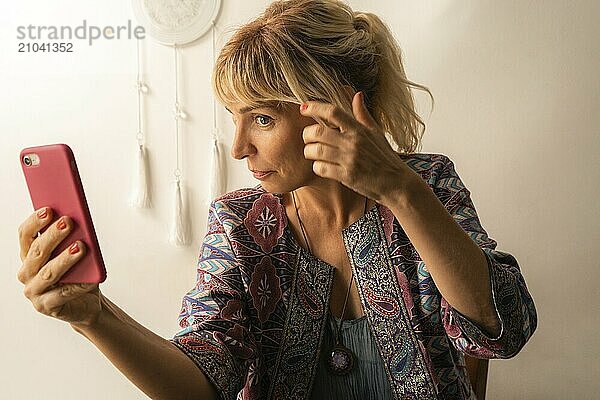 Woman adjusting her hair while looking at the screen of her phone