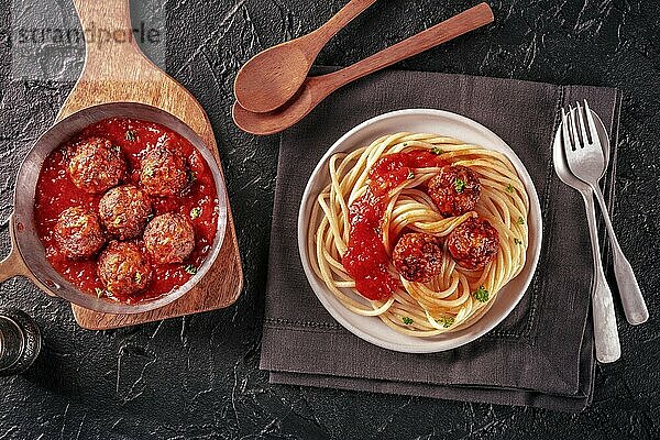 Meatballs. Beef meat balls  overhead flat lay shot in a pan and with a plate of spaghetti pasta  on a black background