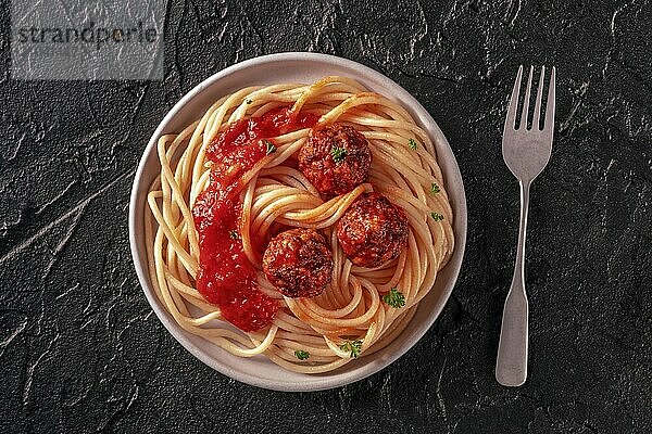 Meatballs. Beef meat balls  overhead flat lay shot with spaghetti pasta  parsley  and tomato sauce  on a black background  Food photography