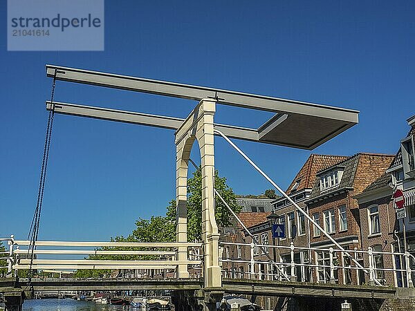 Historic wooden bridge over a canal  surrounded by old buildings on a sunny day  alkmaar  the netherlands