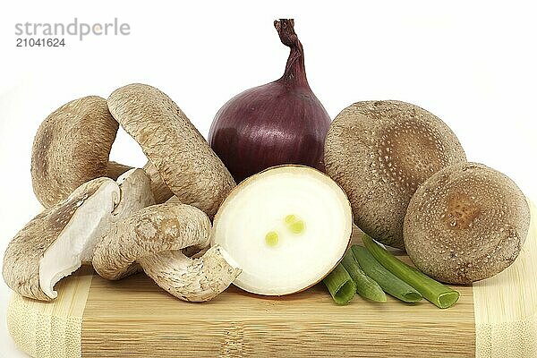 Shiitake mushrooms and various kinds of onions on a wooden cutting board over on white background. Recipes and medicinal herbs