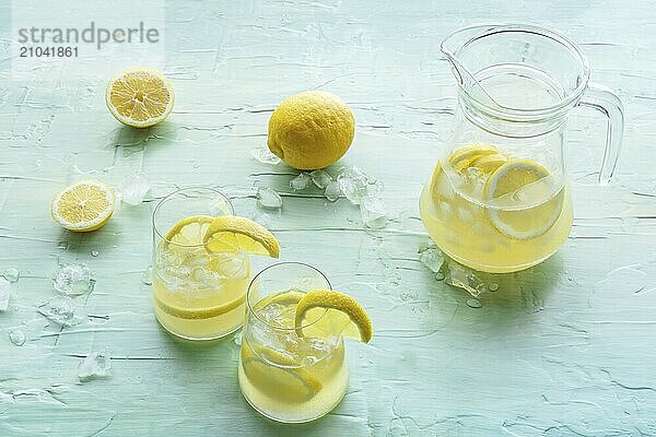 Lemonade. Lemon water drink with ice. Two glasses and a pitcher on a blue background. Detox beverage. Fresh homemade cocktail  Food photography  Food photography