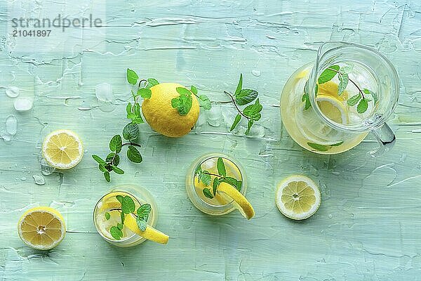 Lemonade with mint. Lemon water drink with ice. Two glasses and a pitcher on a blue background  shot from above. Detox beverage. Fresh homemade cocktail  Food photography