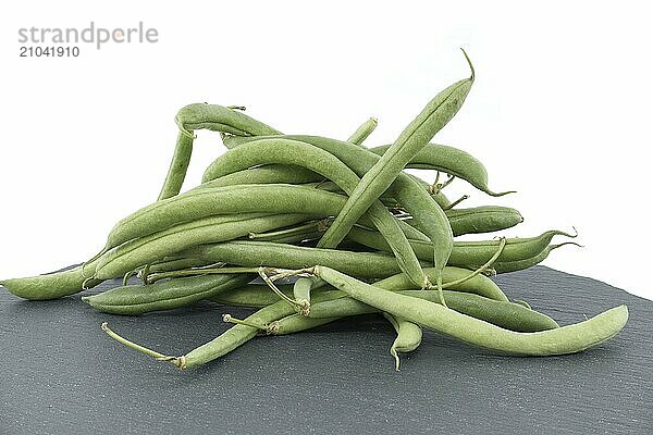 Heap of green beans on black stone table over white background with full depth of field. Organic and diet food