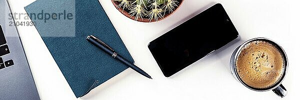 Desk  top view panorama on a white background. Coffee  notebook  phone  plant  and laptop  overhead flat lay shot. Work layout  panoramic banner