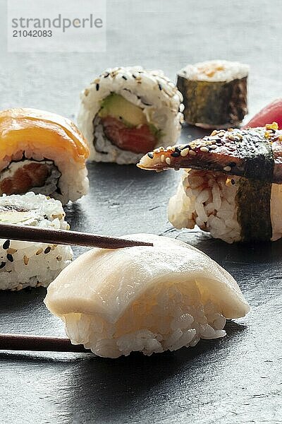 Sushi with chopsticks. Whitefish nigiri and rolls on a black background  Japanese food on a plate at an Asian restaurant  Food photography  Food photography