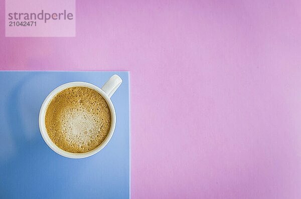 White cup of coffee on light pink and light blue background