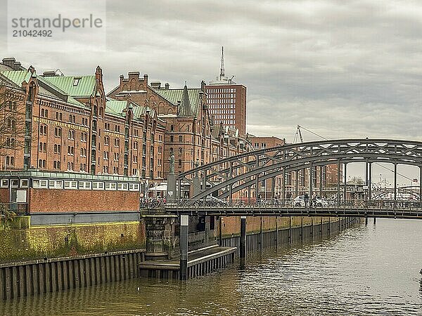 Grey bridge over a river  surrounded by historic brick buildings and a cloudy sky  Hamburg  Germany  Europe