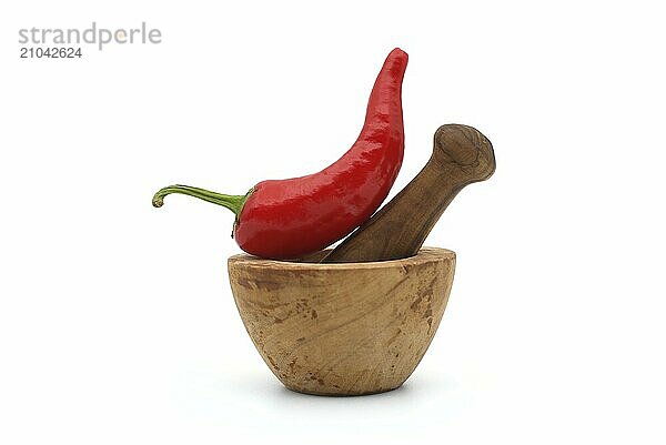 Fresh red chili pepper and old rustic wooden pestle with mortar isolated on a white background