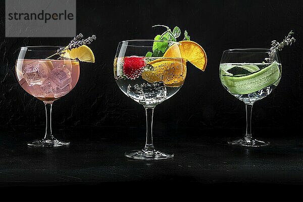 Fancy cocktails with fresh fruit. Gin and tonic drinks with ice at a party  on a black background. Alcohol with lemon  lavender  orange  mint  cucumber  Food photography