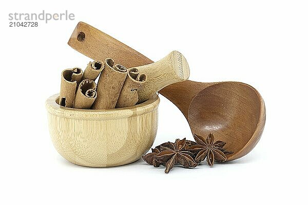 Wooden mortar filled with cinnamon sticks  star anise in a wooden spoon isolated on white background