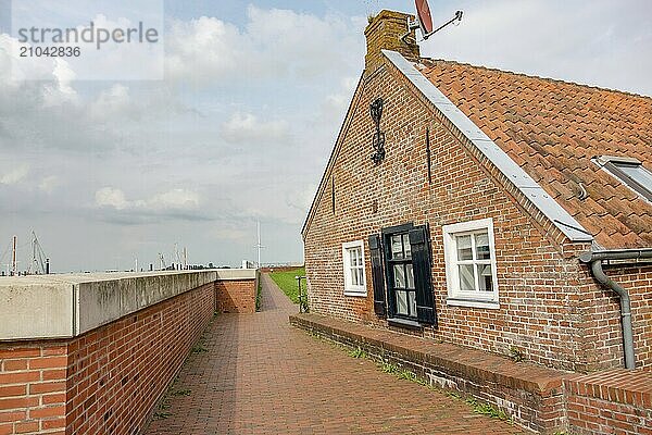 Brick house with tiled roof along a cobbled path on a cloudy day  ditzum  east frisia  germany