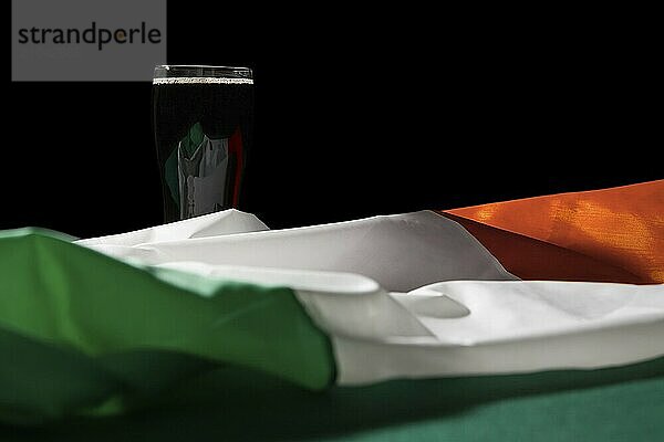 St Patrick day with a pint of black beer and irish flag over a green table and black background