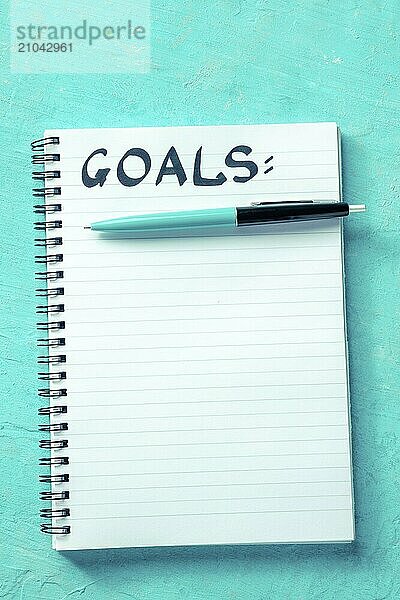 Goal Setting concept. Handwritten word Goals with a pen and a paper notepad  overhead flat lay shot on a vibrant blue background  Food photography