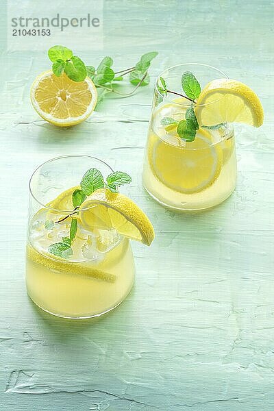 Lemonade with mint. Lemon water drink with ice. Two glasses on a blue background. Detox beverage. Fresh homemade cocktail  Food photography