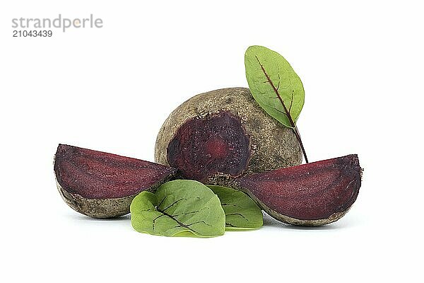 Slices of beetroot showing their purple interior arranged next to whole beetroots vegetables with their green leaves still attached isolated on white background