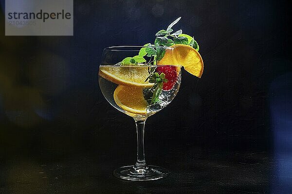 Fancy cocktail with fresh fruit. Gin and tonic drink with ice at a party  on a black background. Alcohol with orange  mint  and strawberry  toned image  Food photography