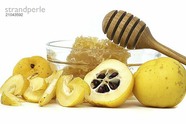 Glass with honey surrounded by vibrant quince fruits  both sliced and whole isolated on white background  full depth of field