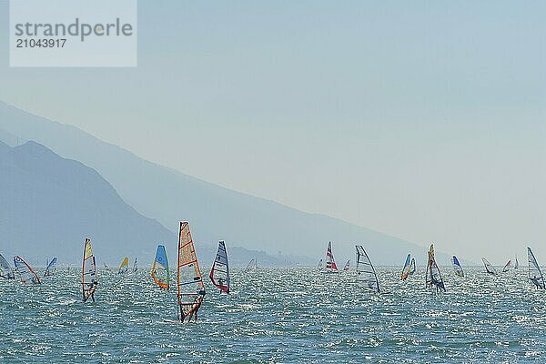 People windsurfing on a sunny day with clear blue skies and mountain backdrop  Lake garda  Torbole  Lake garda  Lago di Garda  Trentino  Italy  Europe