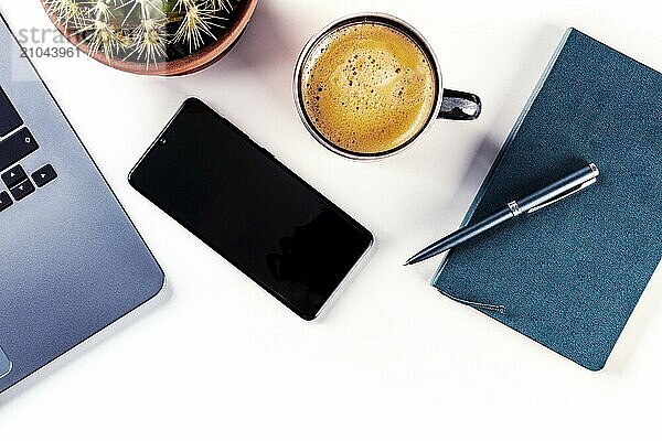 Desk  top view on a white background. Coffee  notebook  phone  plant  and laptop  overhead flat lay shot. Work layout with copy space