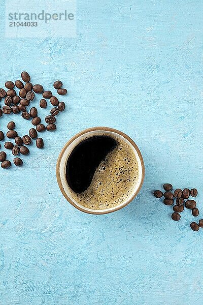 Coffee cup and beans  shot from above on a blue background with a place for text  Food photography