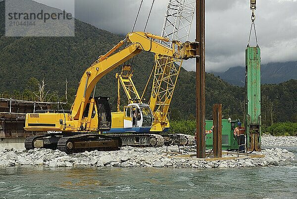 Builders drive pylons for a concrete bridge over a river in Westland  New Zealand  Oceania