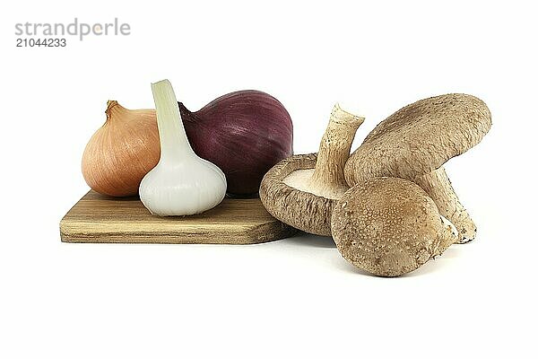 Shiitake mushrooms and various onions on a wooden cutting board isolated on white background. Recipes and medicinal herbs