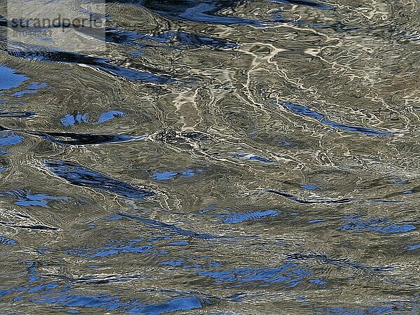 The colours of the blue sky and the trees on the banks are reflected in the Saale river in Saxony