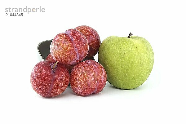 Collection of fresh fruits comprising red plums and bright green apple arranged against a white background