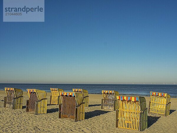 Several colourful beach chairs on a sunny beach with a view of the sea and wind turbines  egmond aan zee  the netherlands