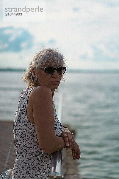 Portrait of senior woman standing against railing.