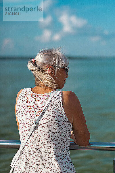 Portrait of senior woman standing against railing.