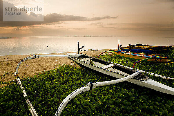 Traditional outrigger fishing boat on a Bali beach at sunrise  Indonesia.