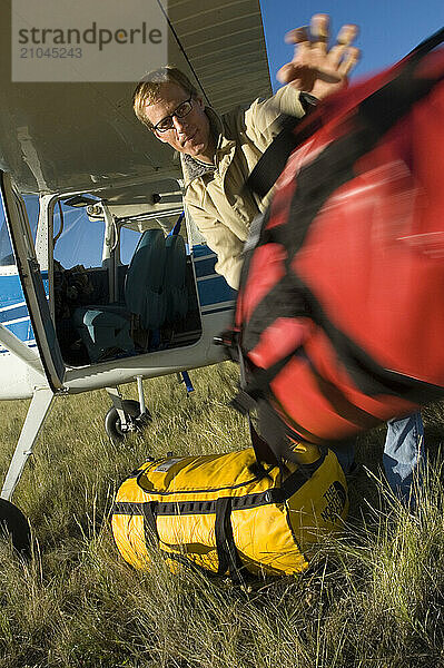 A man unloads baggage from his airplane near Bozeman  Montana.