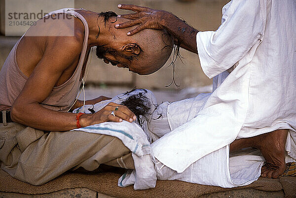 Indian Hindu Pilgrim receiving a traditional hair cut  Ganges Sacred River  Varanasi  Uttar Pradesh  India.