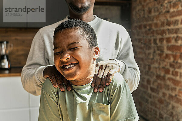 African American man makes laugh his son cuddling