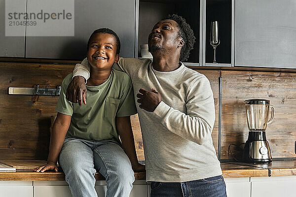 African American father and boy having fun and laughing in kitchen