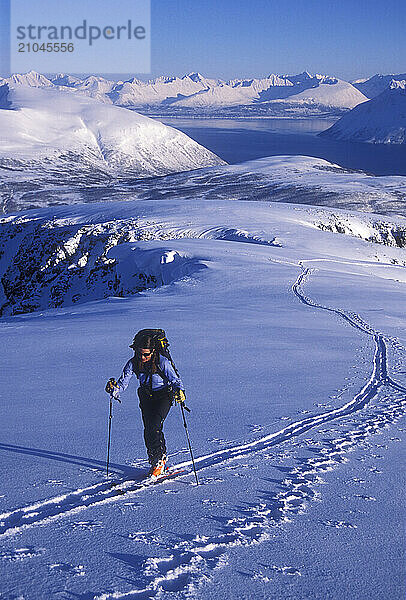 A woman ski tours and explores the mountains of the Lyngen Alps in Norway.