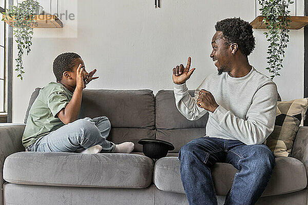 African American father and boy having fun playing charades game