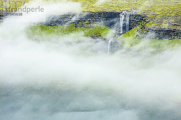 Fossa waterfall emerging from fog  Faroe Islands