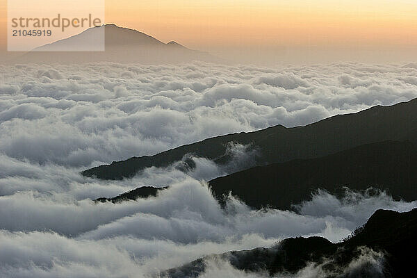 Above the clouds view of Mount Meru in the distance taken from Mount Kilimanjaro.