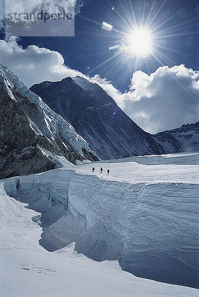 Three mountaineers walk across a glacier below the summit of Mount Everest  Nepal.