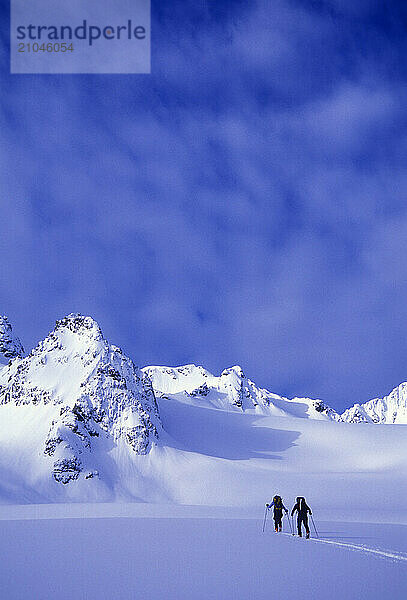 A man and woman ski tour and explore the mountains of the Lyngen Alps in Norway.