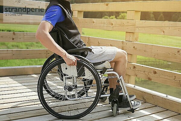 Behinderter junger Mann in einem Rollstuhl  der die Räder mit der Hand hält und dreht