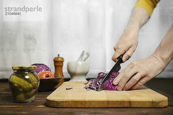 Unbekannter Mann schneidet Rotkohl in der Küche