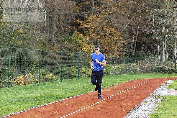 Junger Mann joggt morgens im Freien auf der Laufstrecke